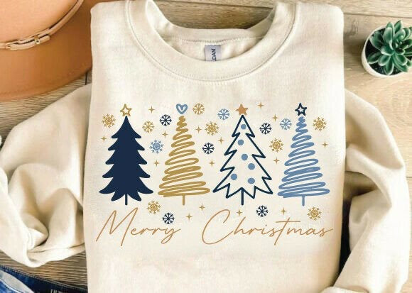 Folded beige sweatshirt with Christmas tree designs and 'Merry Christmas' text on a wooden surface.