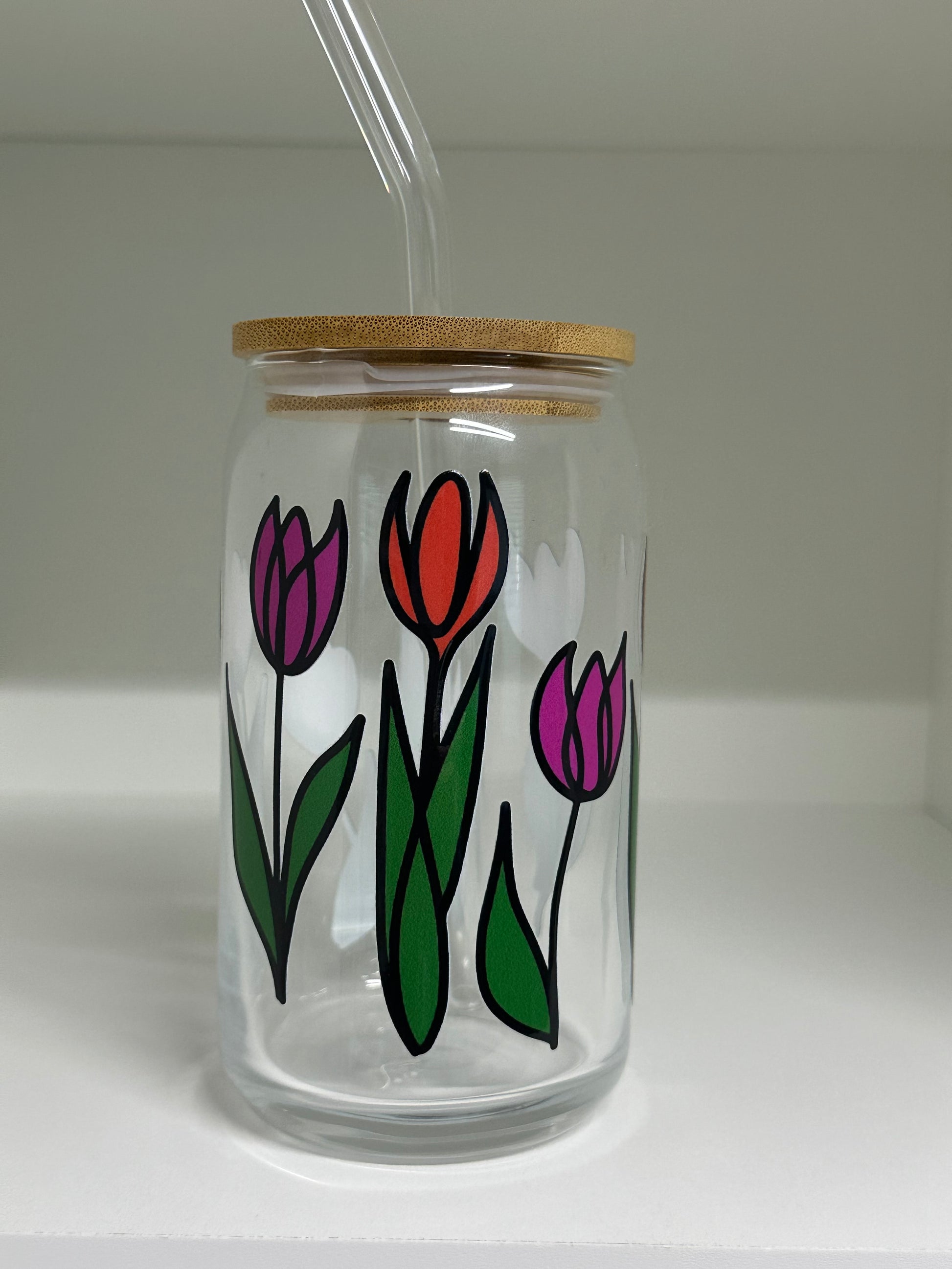 16 oz Glass jar with floral design and wooden lid on a clear background