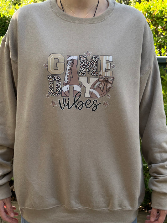 Beige sweatshirt with 'Girl Vibes' text and patterns held by a person outdoors.