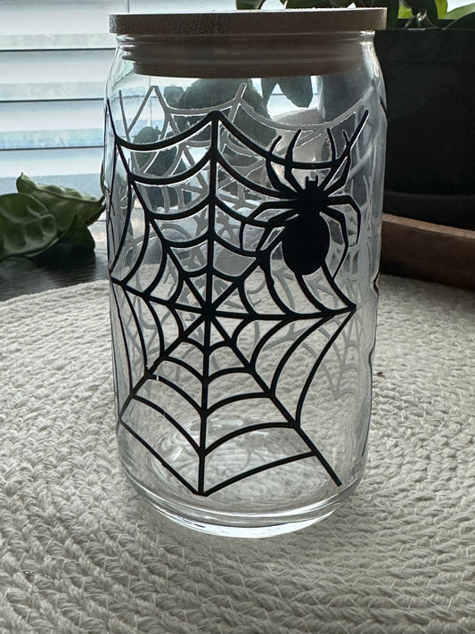 Glass tumbler with spider and web design on a textured wall background