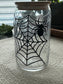 Glass tumbler with spider and web design on a textured wall background
