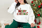 Person wearing a white sweatshirt with 'Merry Christmas' text and reindeer design in front of a decorated Christmas tree.